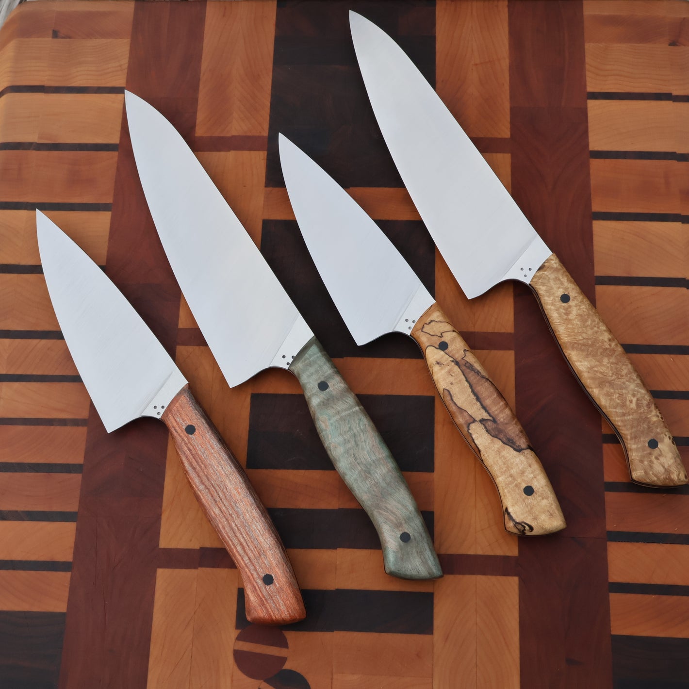 Four knives with wooden handles on a striped wooden surface