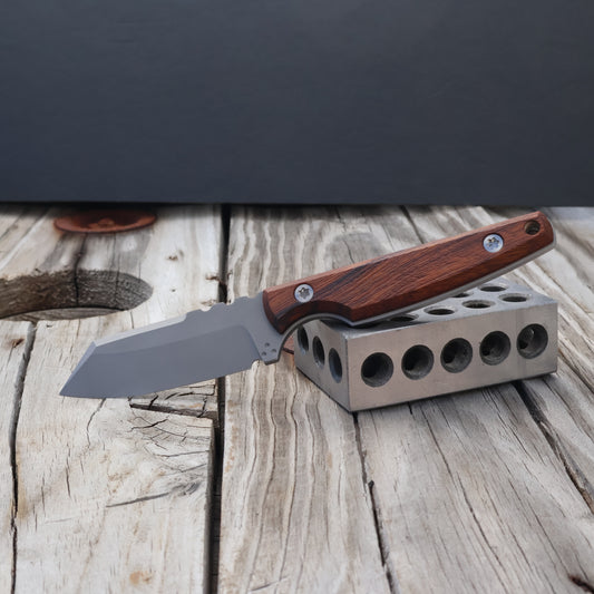 Knife with wooden handle on a metal block against a dark background