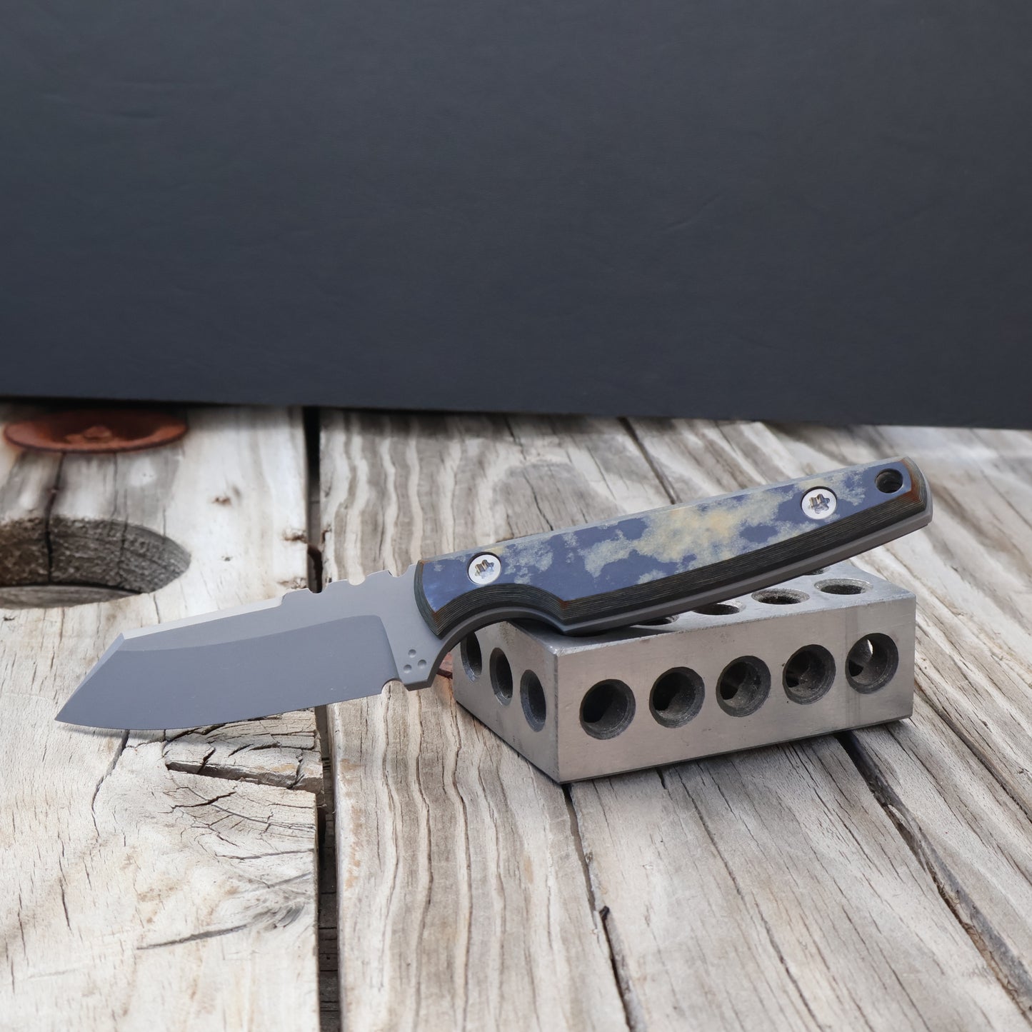 fixed blade knife with nautical richlite handle on a metal block against a black background