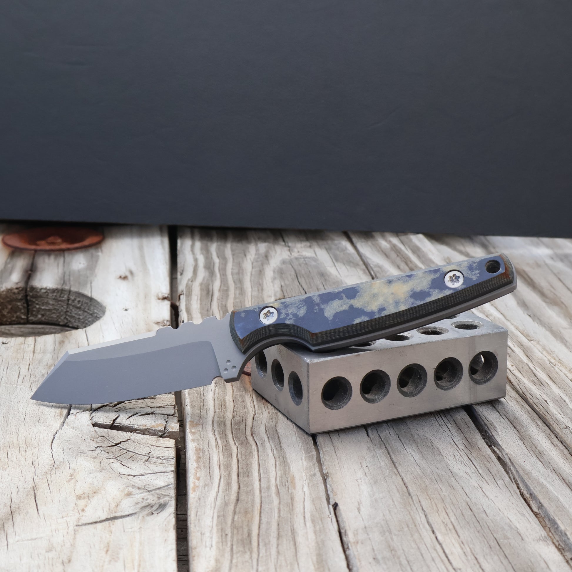 fixed blade knife with nautical richlite handle on a metal block against a black background