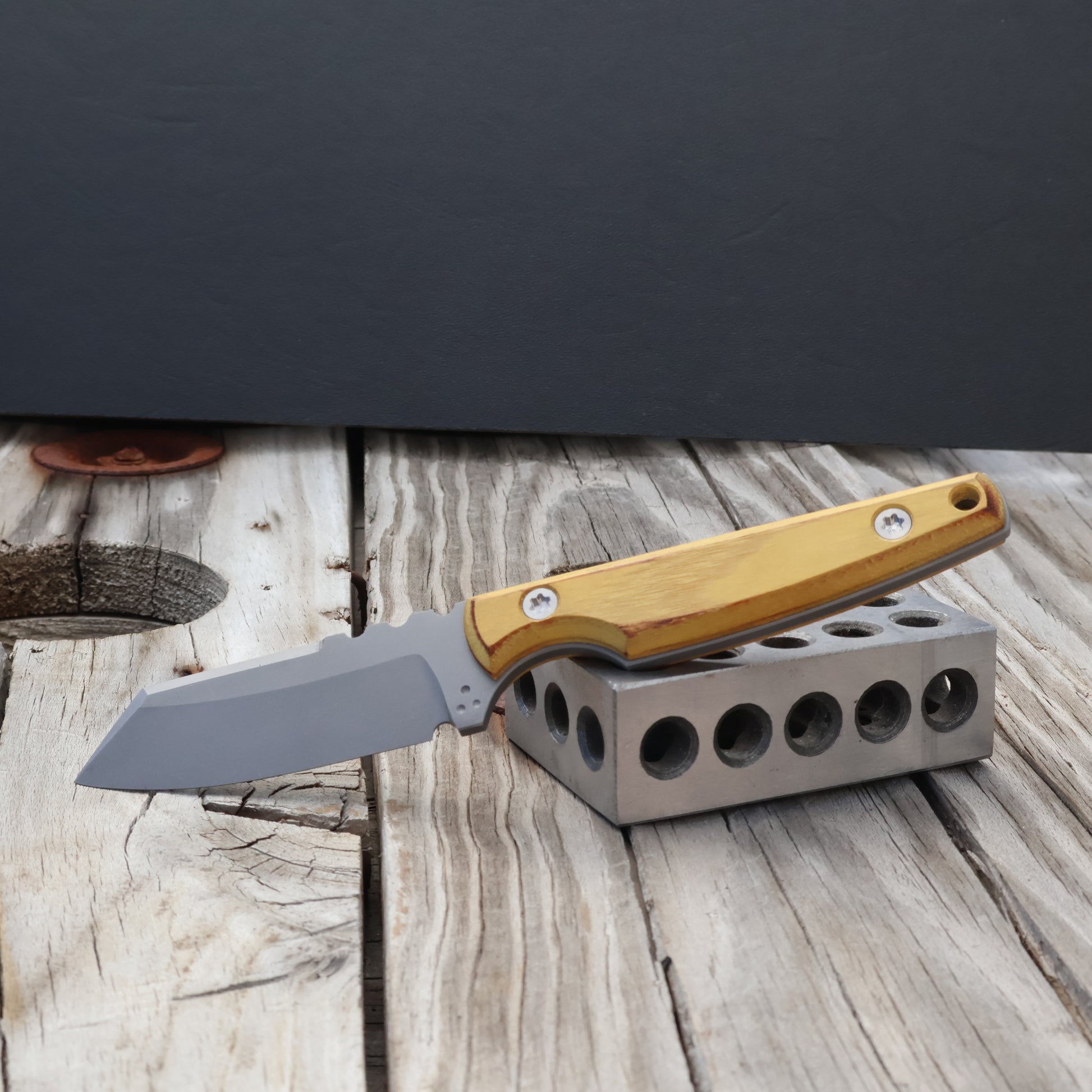 fixed blade knife with charred osage orange wood handle resting on metal block