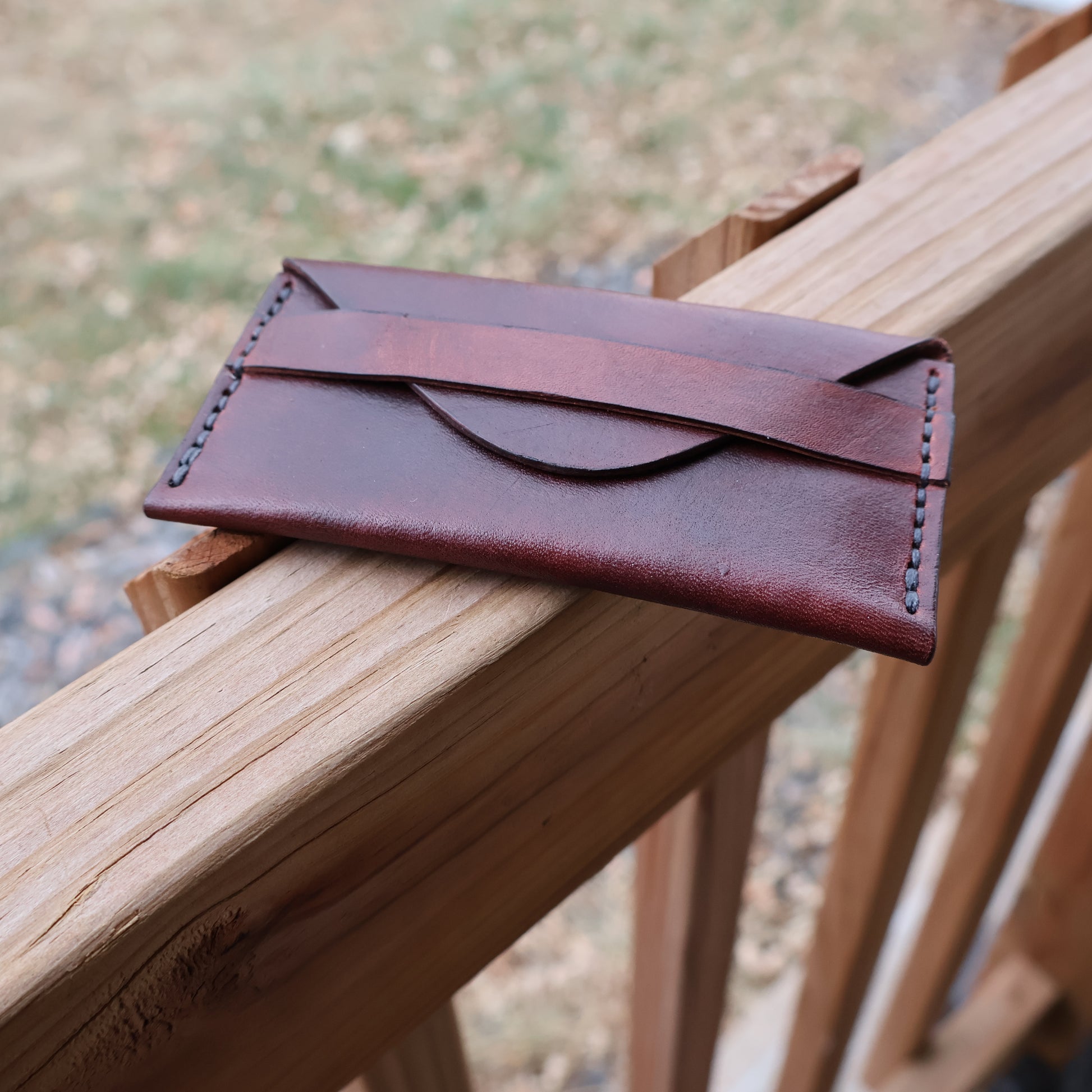 Small leather wallet sitting on wooden railing