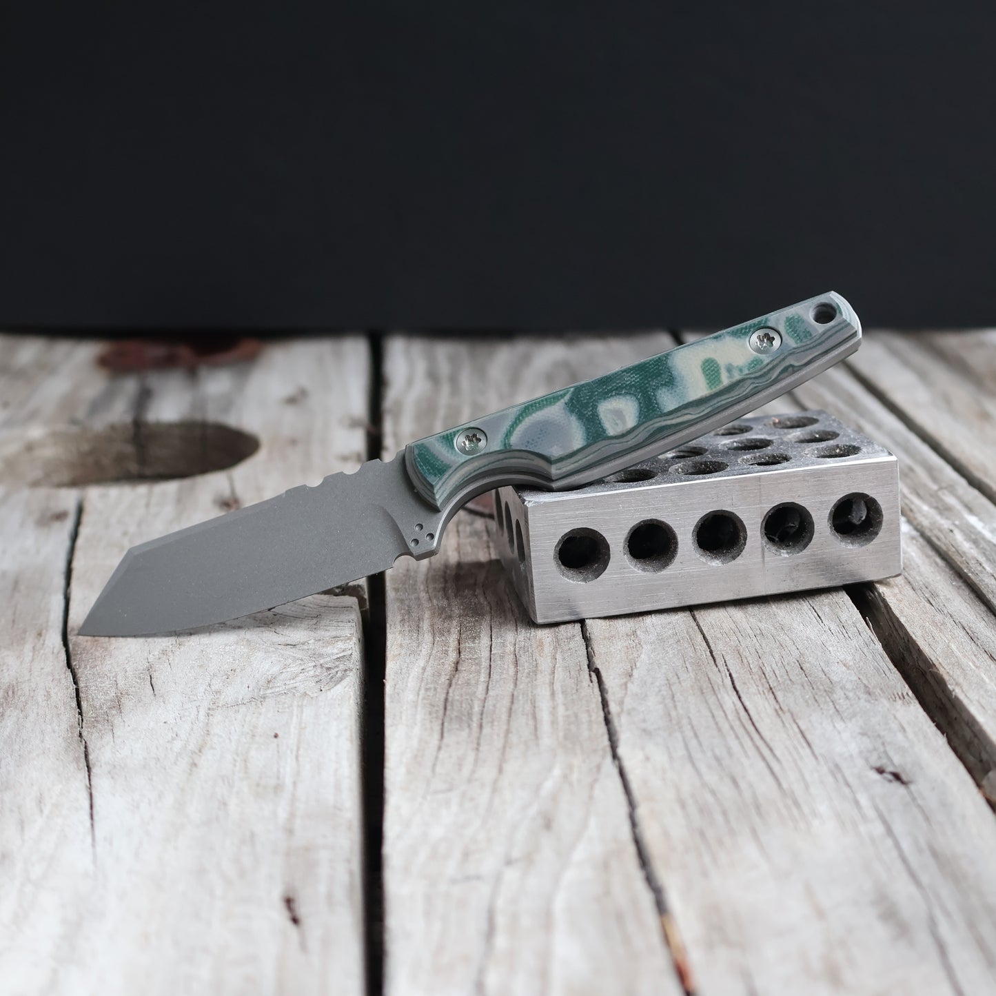 fixed blade knife with green handle on wood surface 