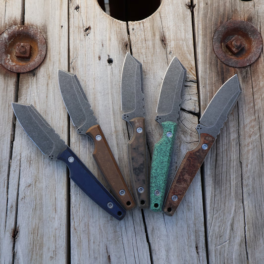 Five Fixed blade knives sitting on wooden surface 