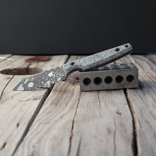 Knife with a speckled blade & handle on a wooden surface