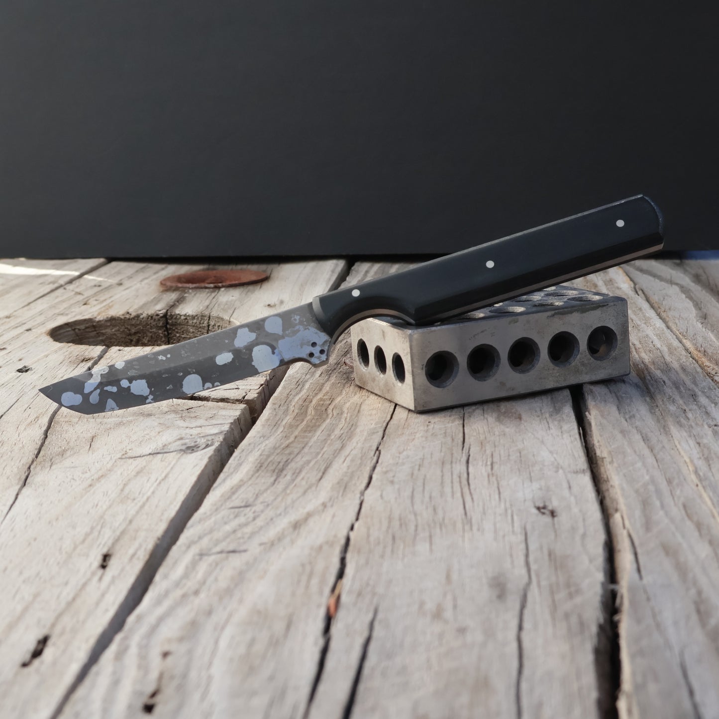 Knife with a black handle on a wooden surface against a dark background