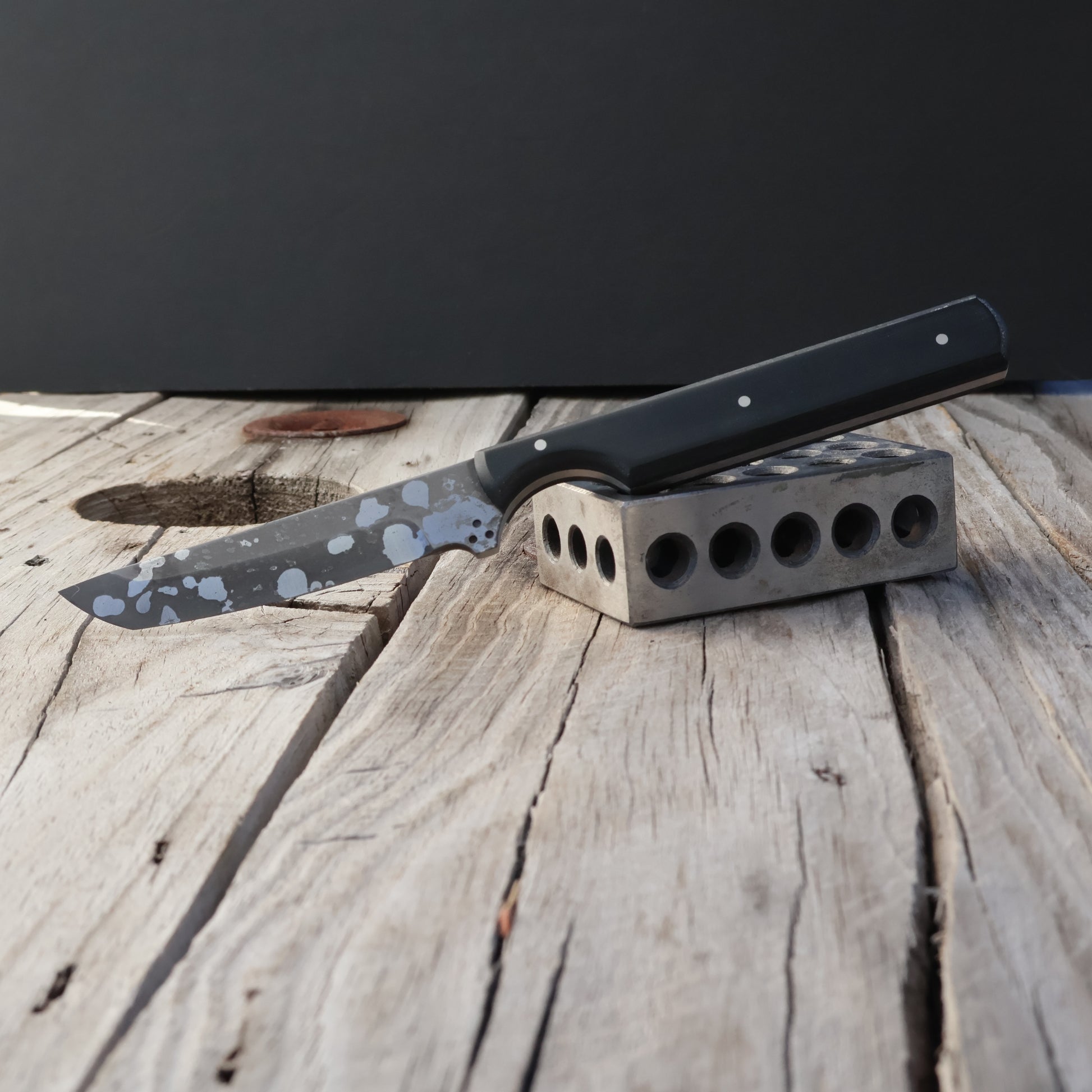 Knife with a black handle on a wooden surface against a dark background