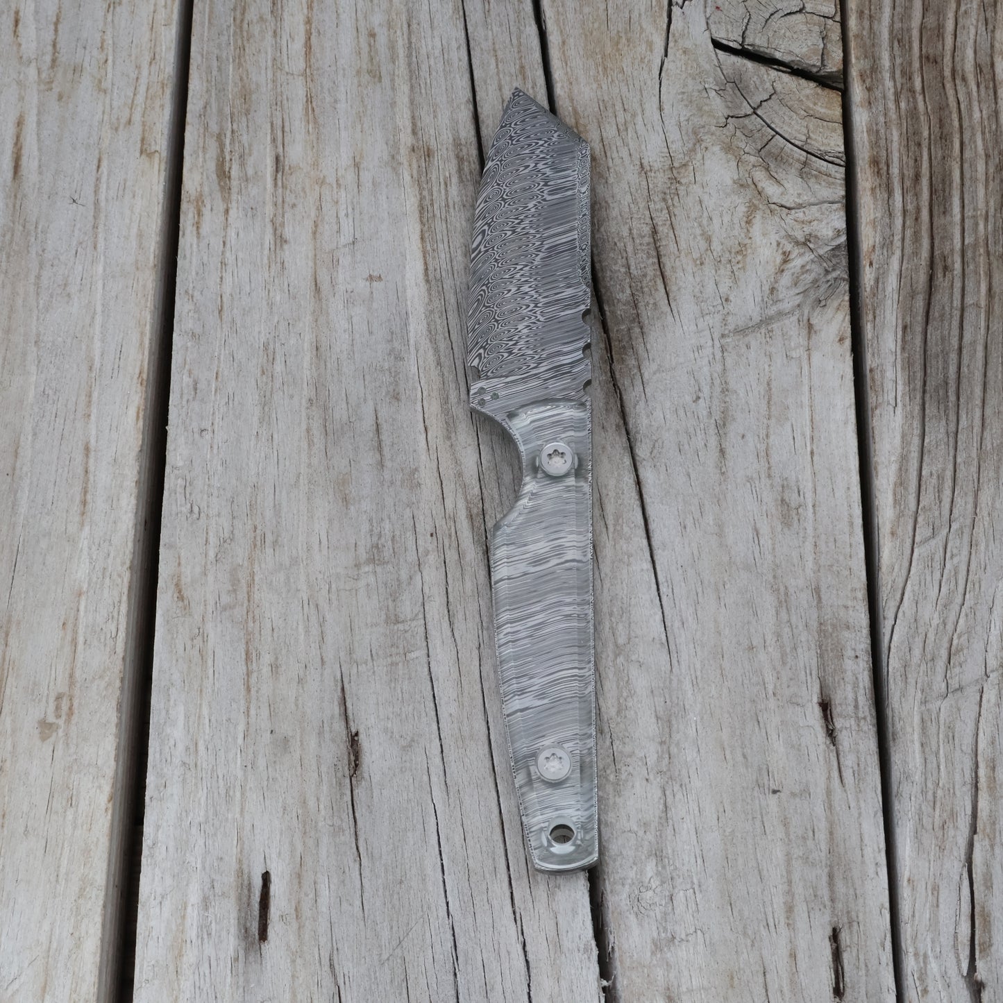 Handcrafted knife with a textured blade and clear handle on a wooden surface
