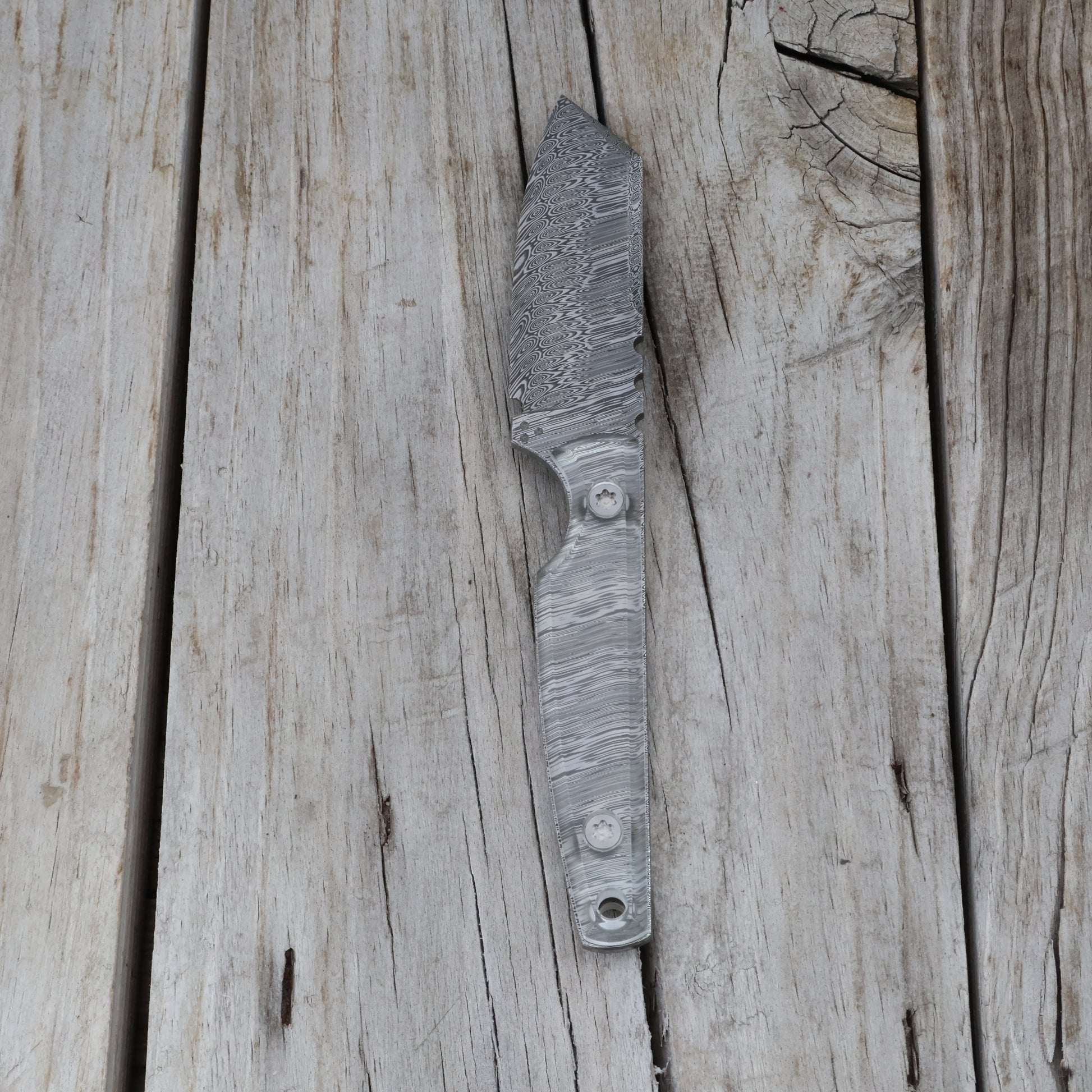 Handcrafted knife with a textured blade and clear handle on a wooden surface