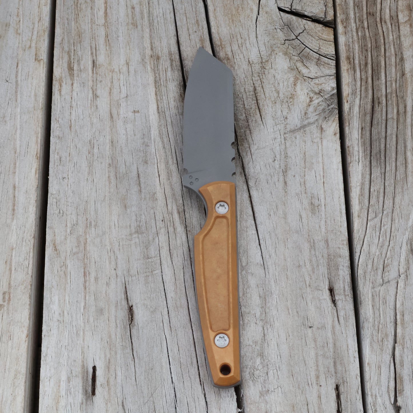 Knife with a pocketed tan handle on a wooden surface