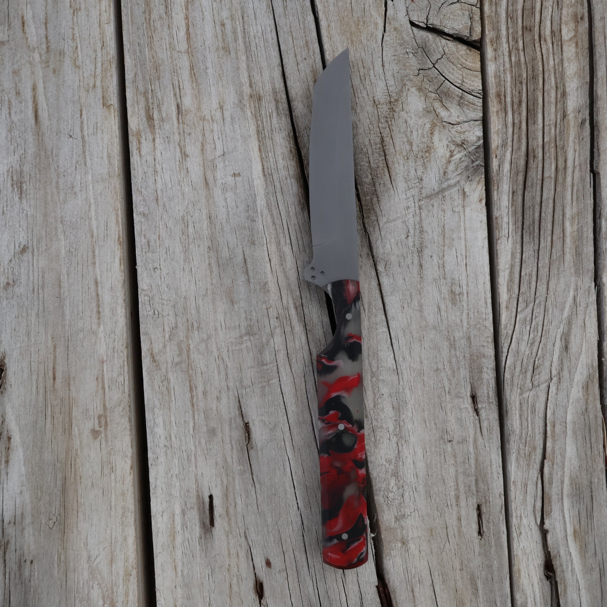 Knife with a red and black handle on a wooden surface
