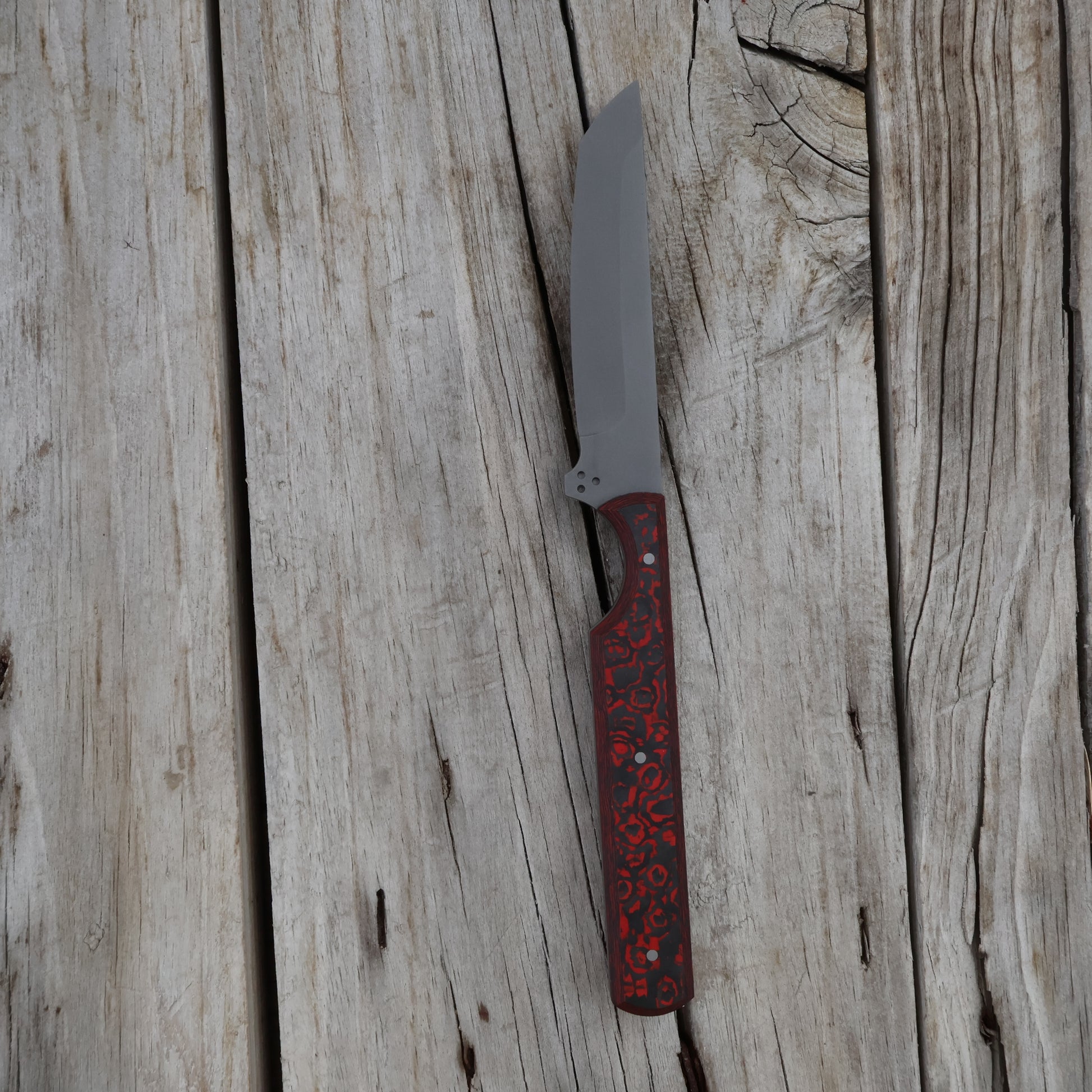 Knife with a red and black carbon handle on a wooden surface