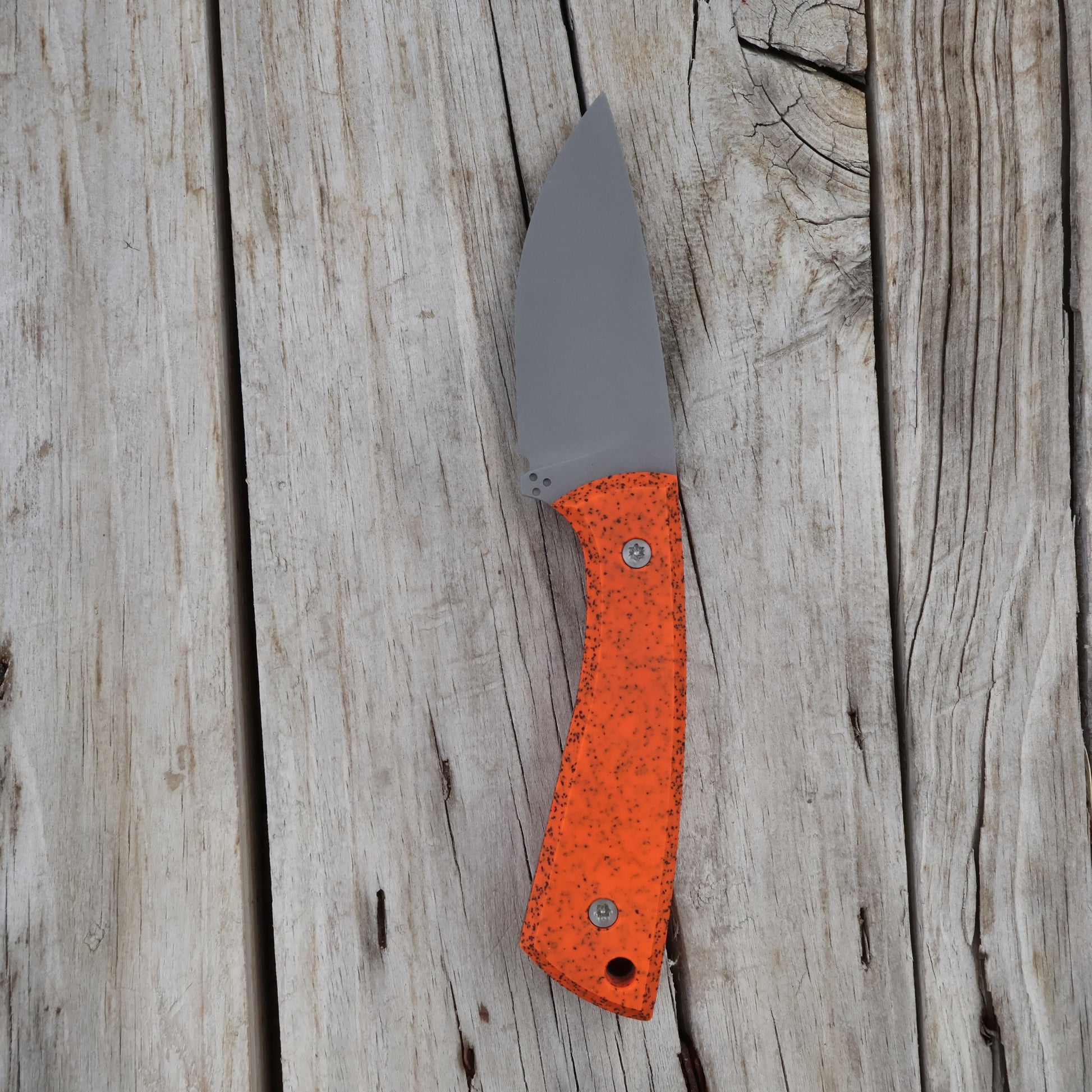 knife with an orange handle on a wooden surface