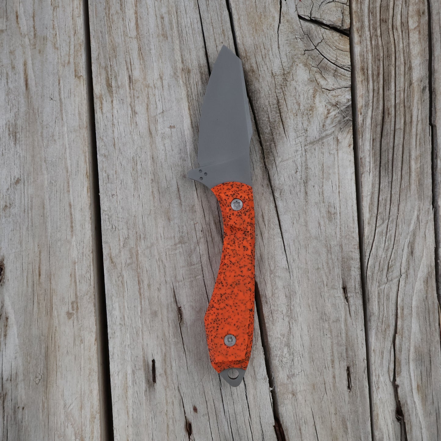 Knife with orange handle on a wooden surface