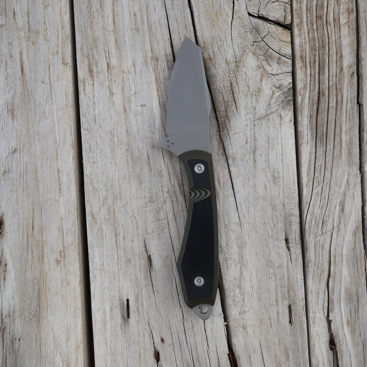 Knife with a black and green handle on a wooden surface