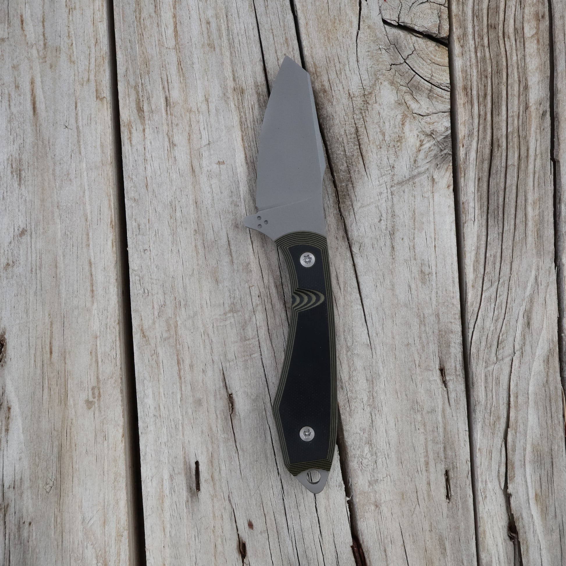 Knife with a black and green handle on a wooden surface