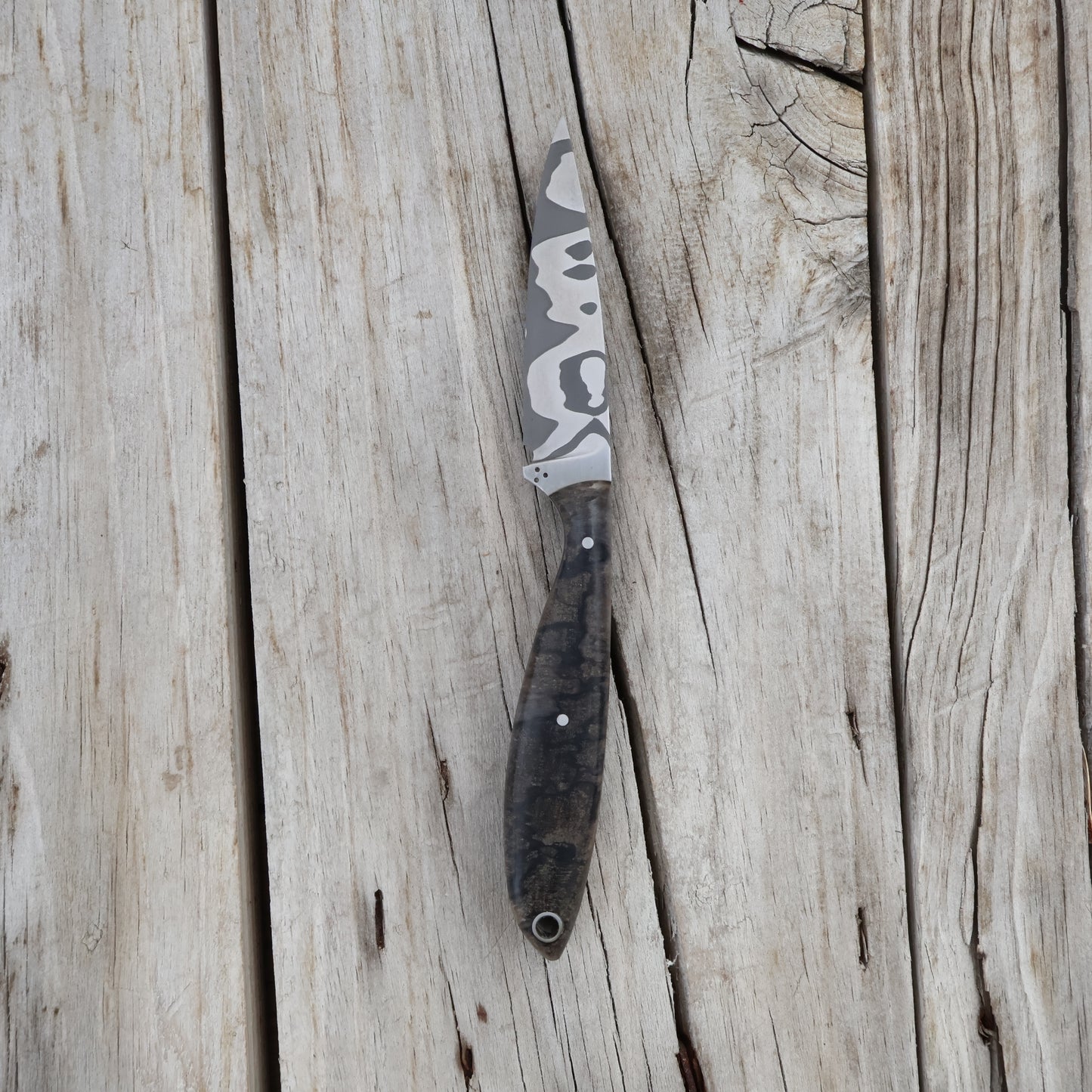 Fishing knife with damascus blade on a wooden surface