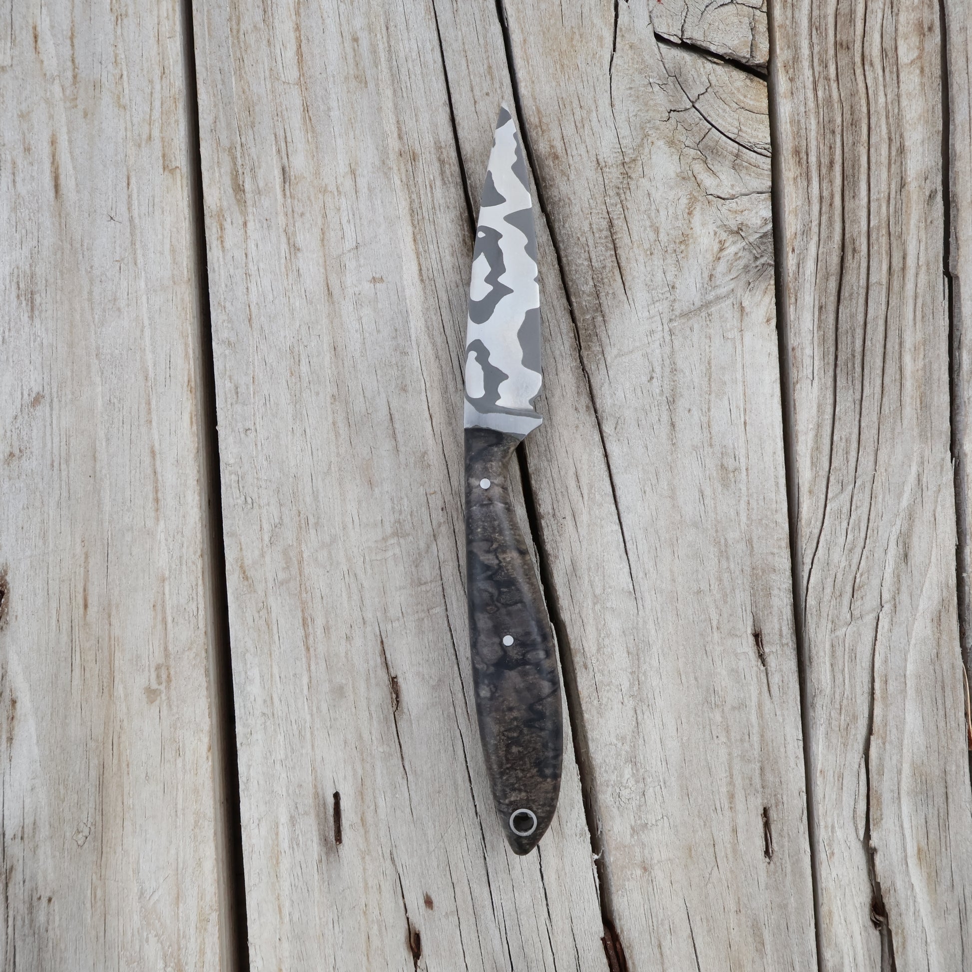 Knife with a damascusblade and wooden handle on a wooden surface