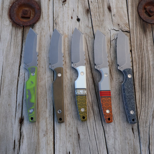 Five knives with various colored handles on a wooden surface