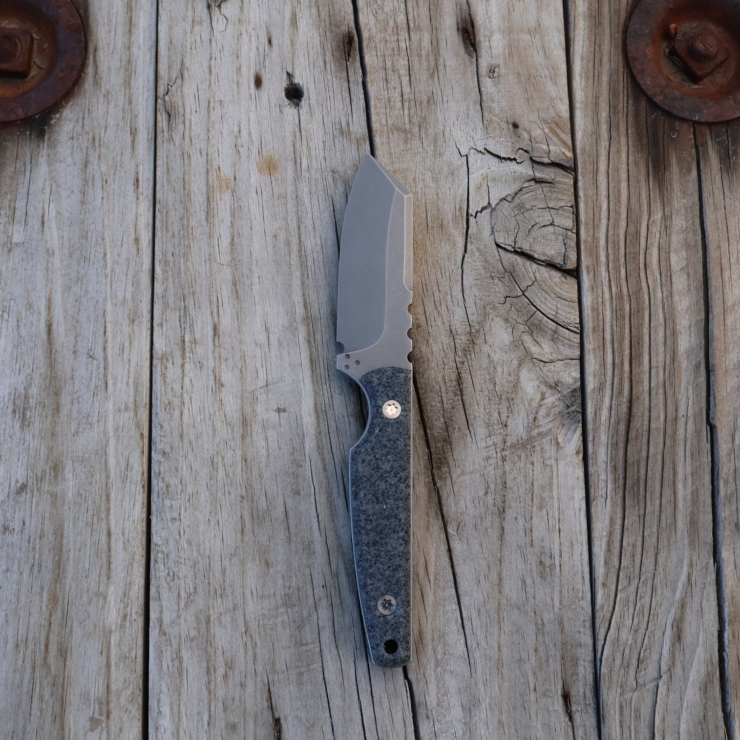 fixed blade  knife with a gray textured handle on a wooden surface