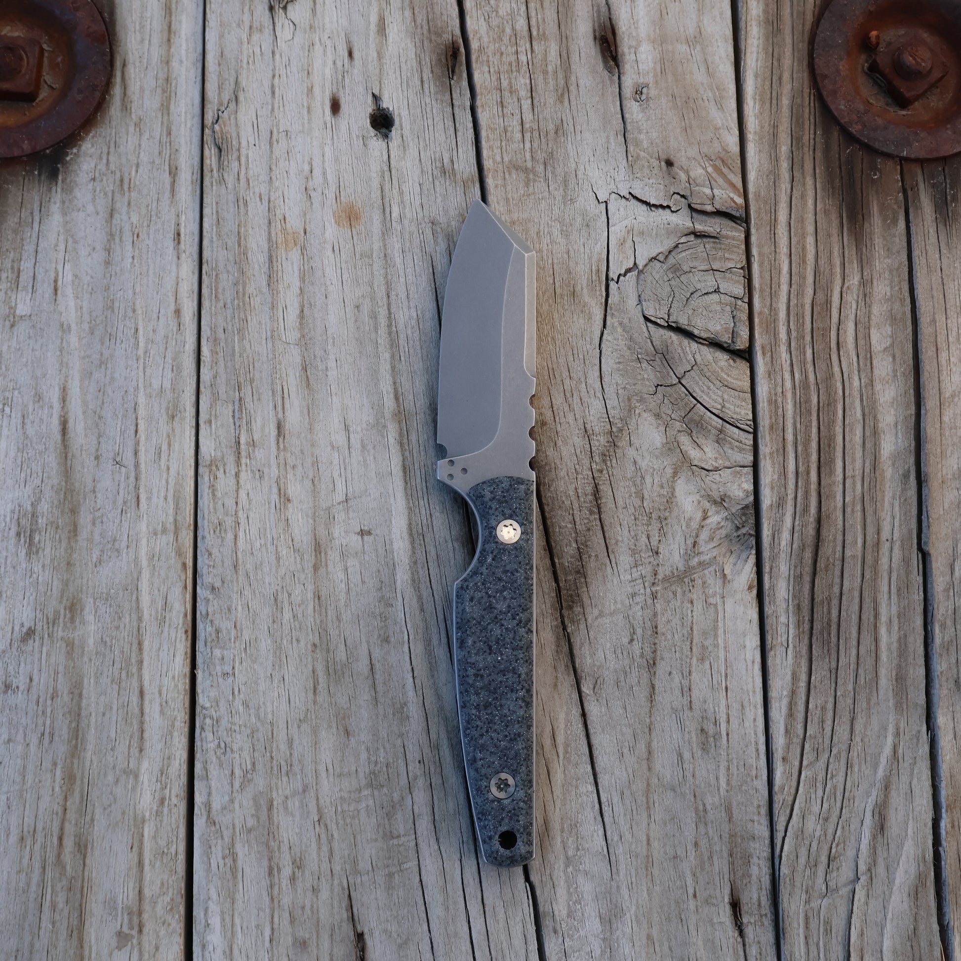 fixed blade  knife with a gray textured handle on a wooden surface