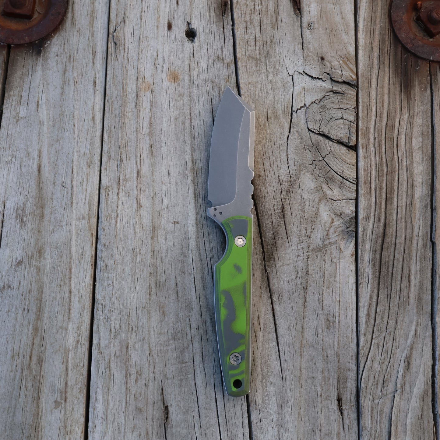 fixed blade knife with a green and gray handle on a wooden surface