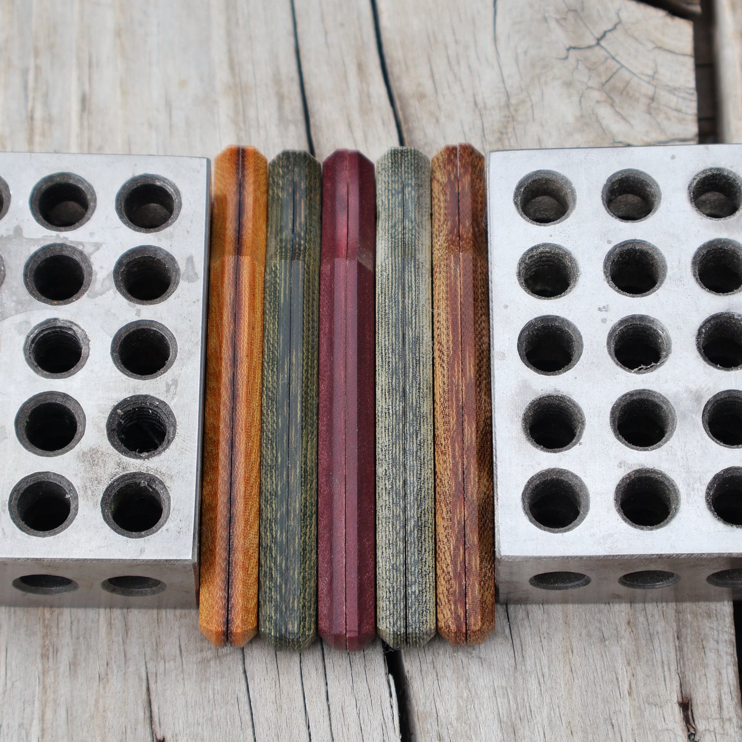 five knife handle scales set on edge between metal blocks