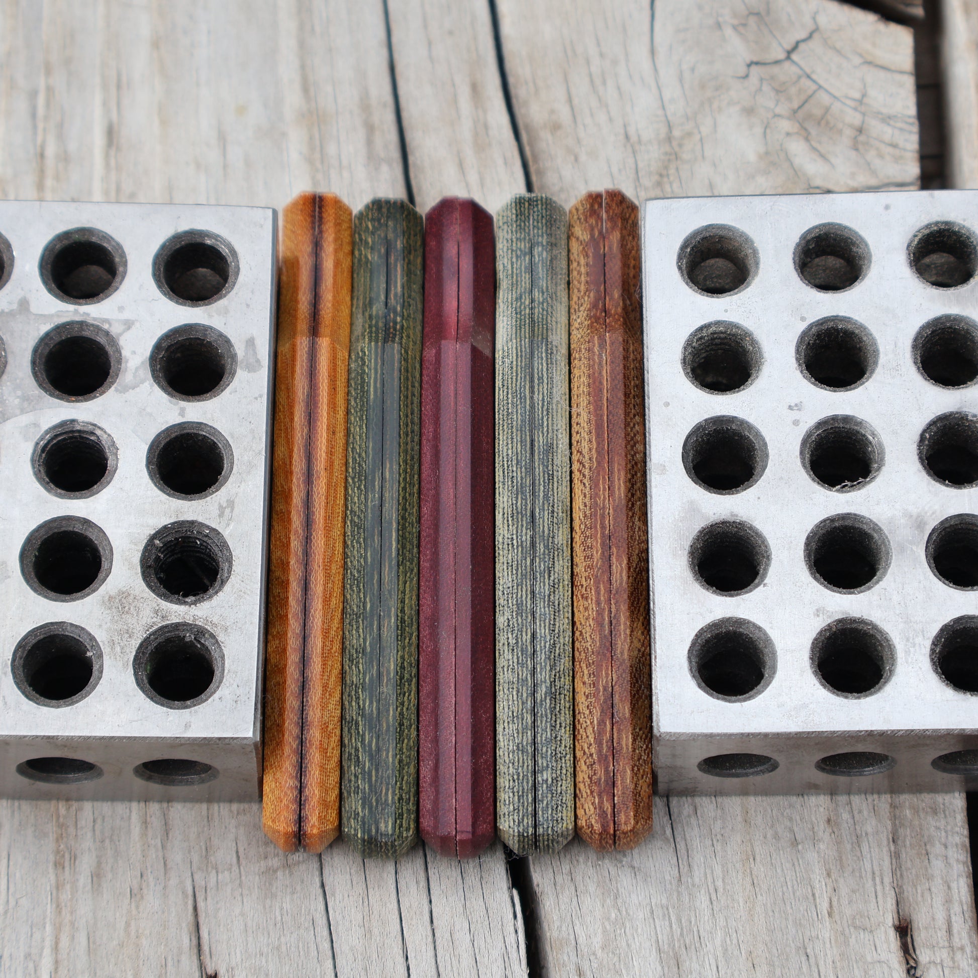five knife handle scales set on edge between metal blocks