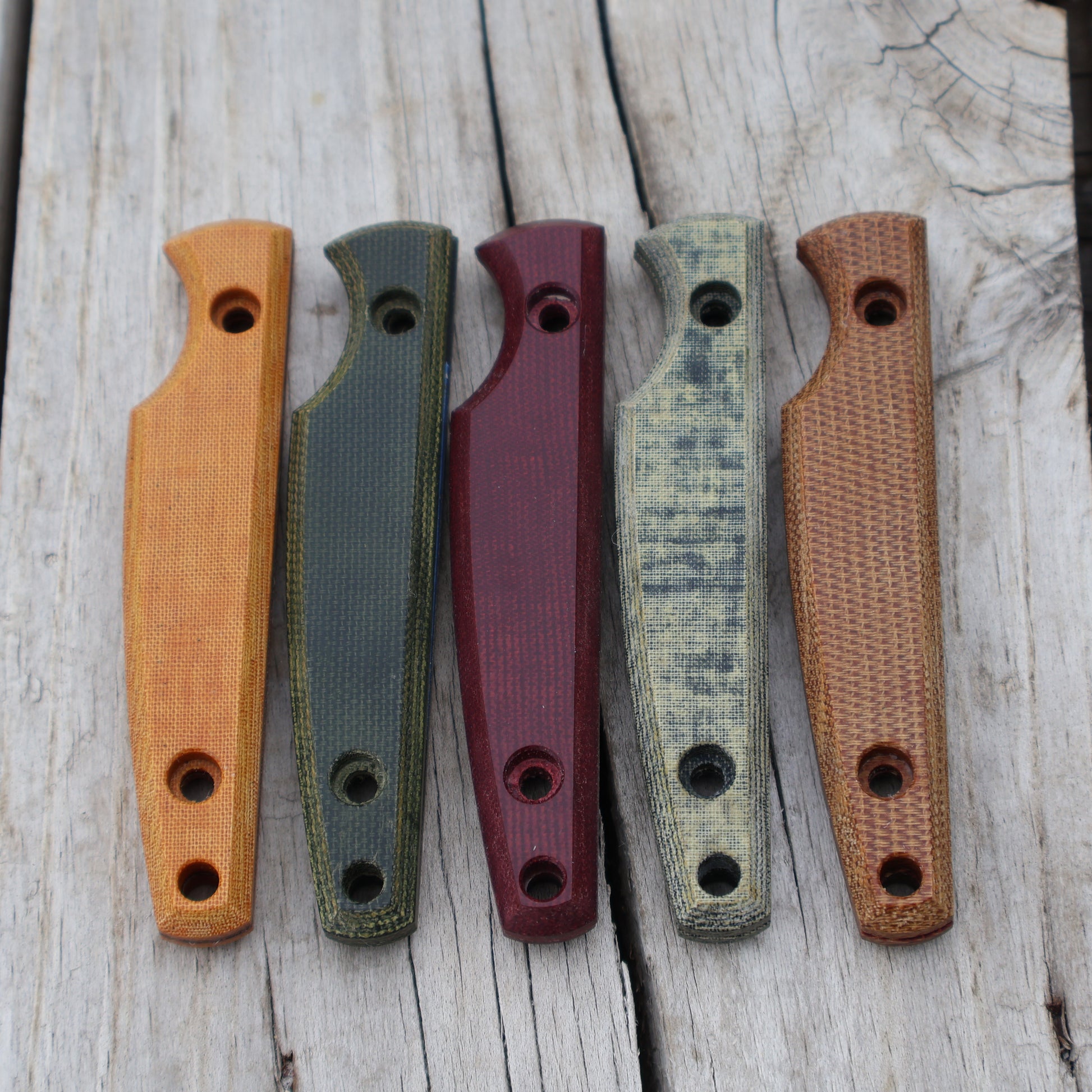 Five knife handles in different colors on a wooden surface