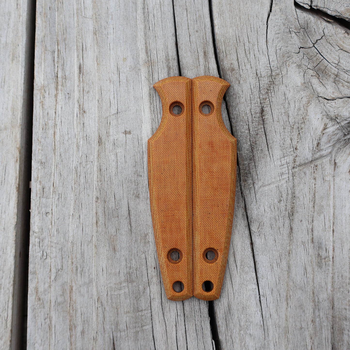 Pair of tan knife scales on a wooden surface