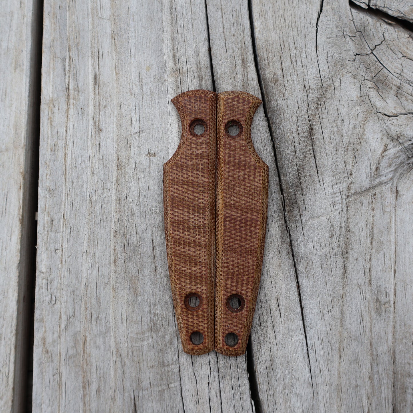 Pair of brown knife handle scales on wooden surface 