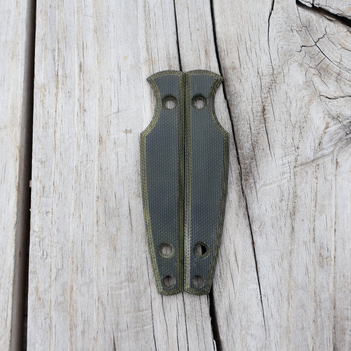 Pair of green knife handle scales on wooden surface 