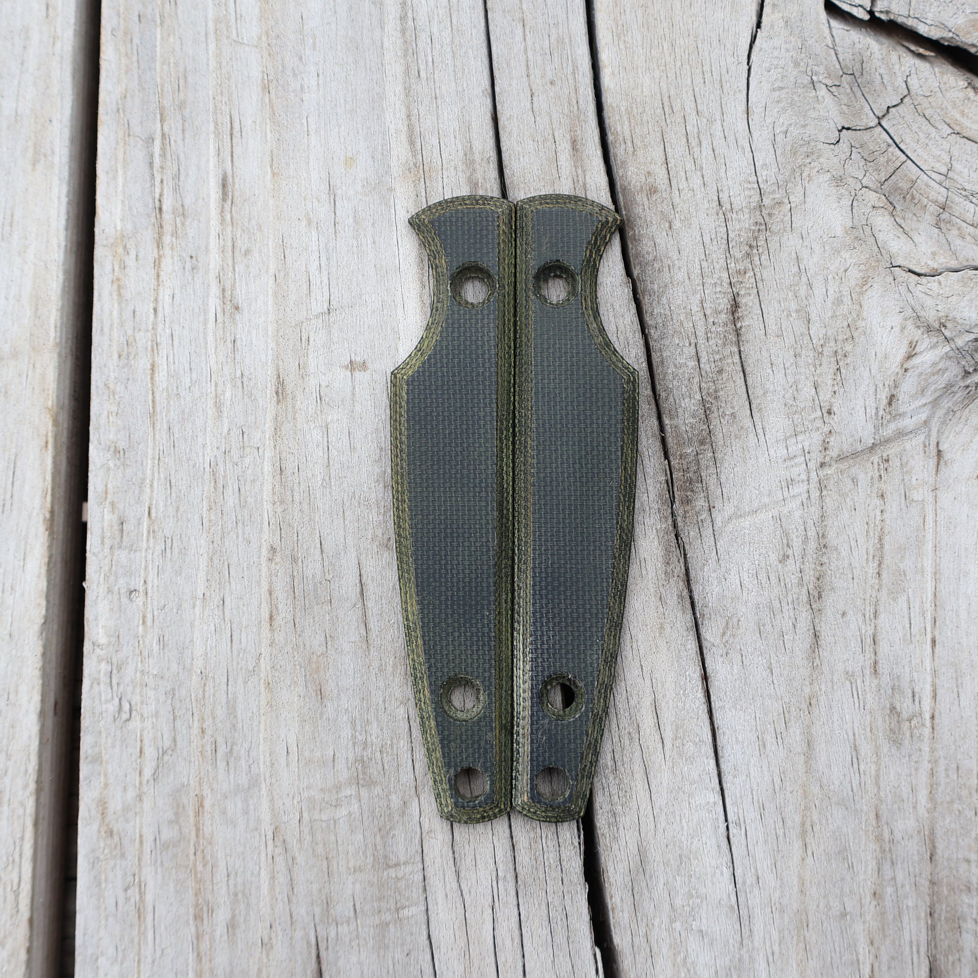 Pair of green knife handle scales on wooden surface 