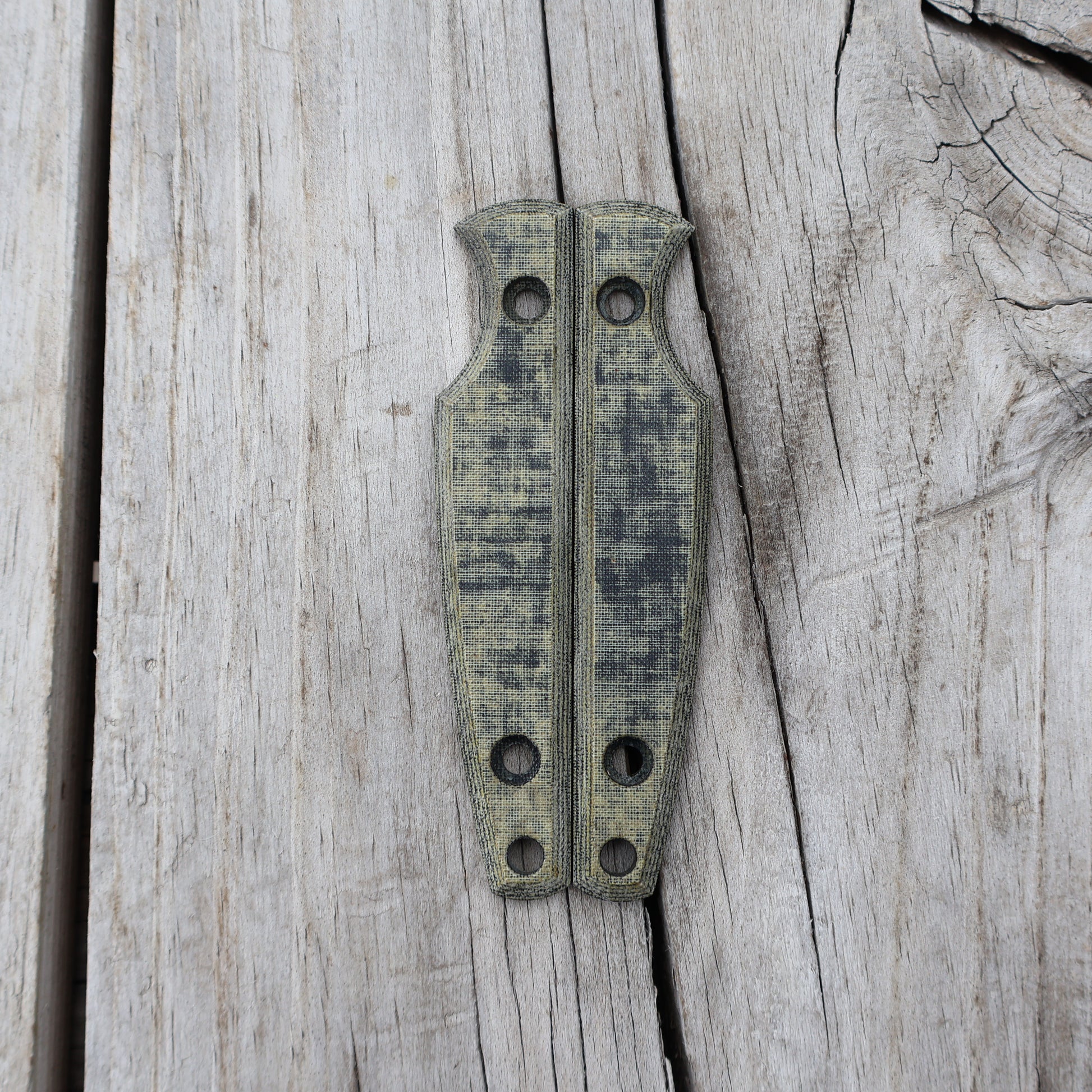 Pair of green/black knife handle scales on wooden surface 