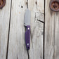 Knife with textured purple handle on wooden surface 