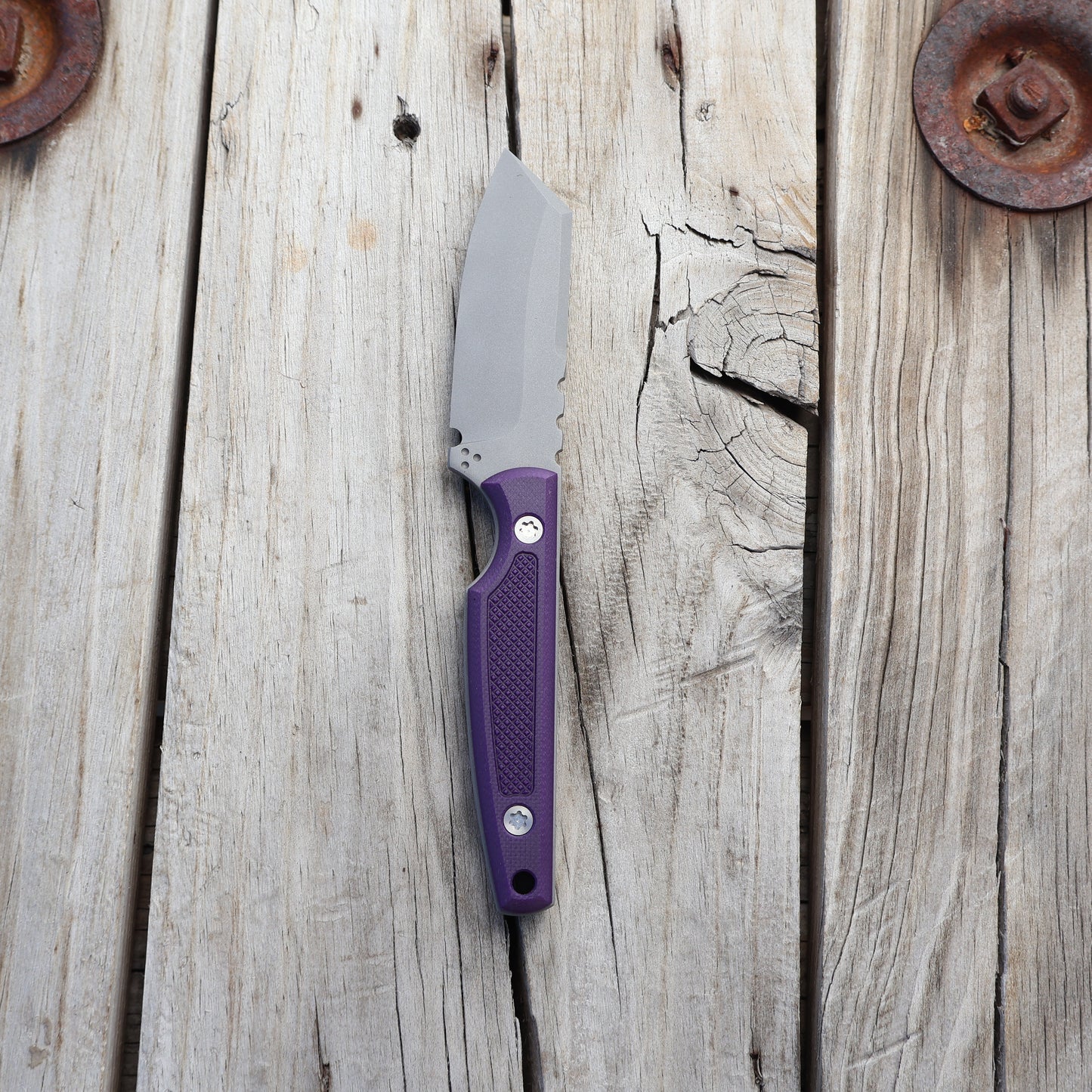 Knife with textured purple handle on wooden surface 