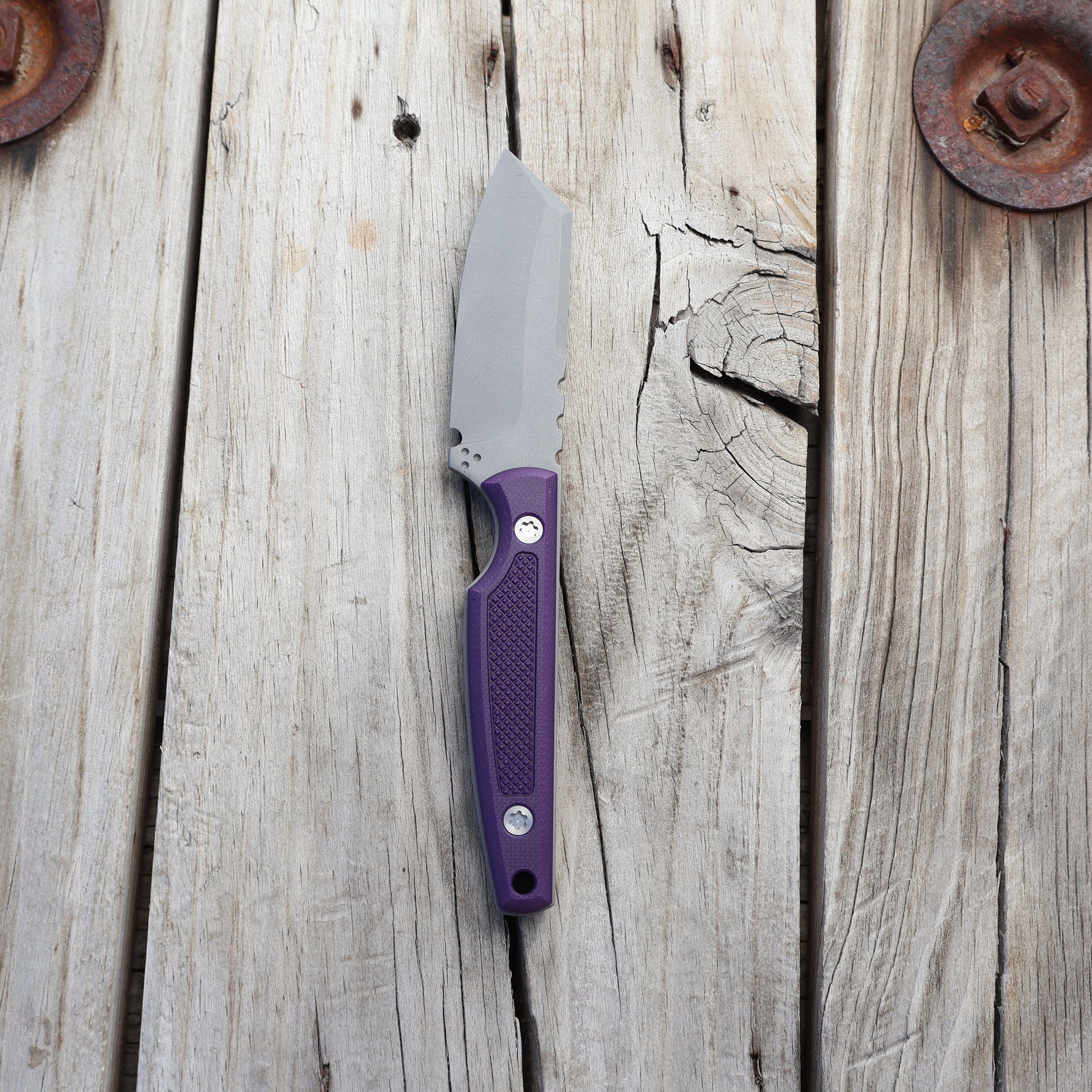 Knife with textured purple handle on wooden surface 