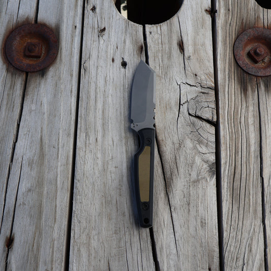 fixed blade knife with green and black handle sitting on wooden surface