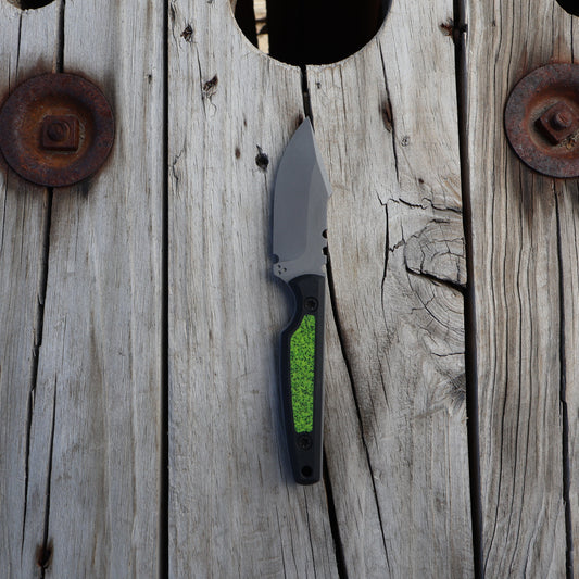 fixed blade knife with chartreuse and black handle sitting on wooden surface  
