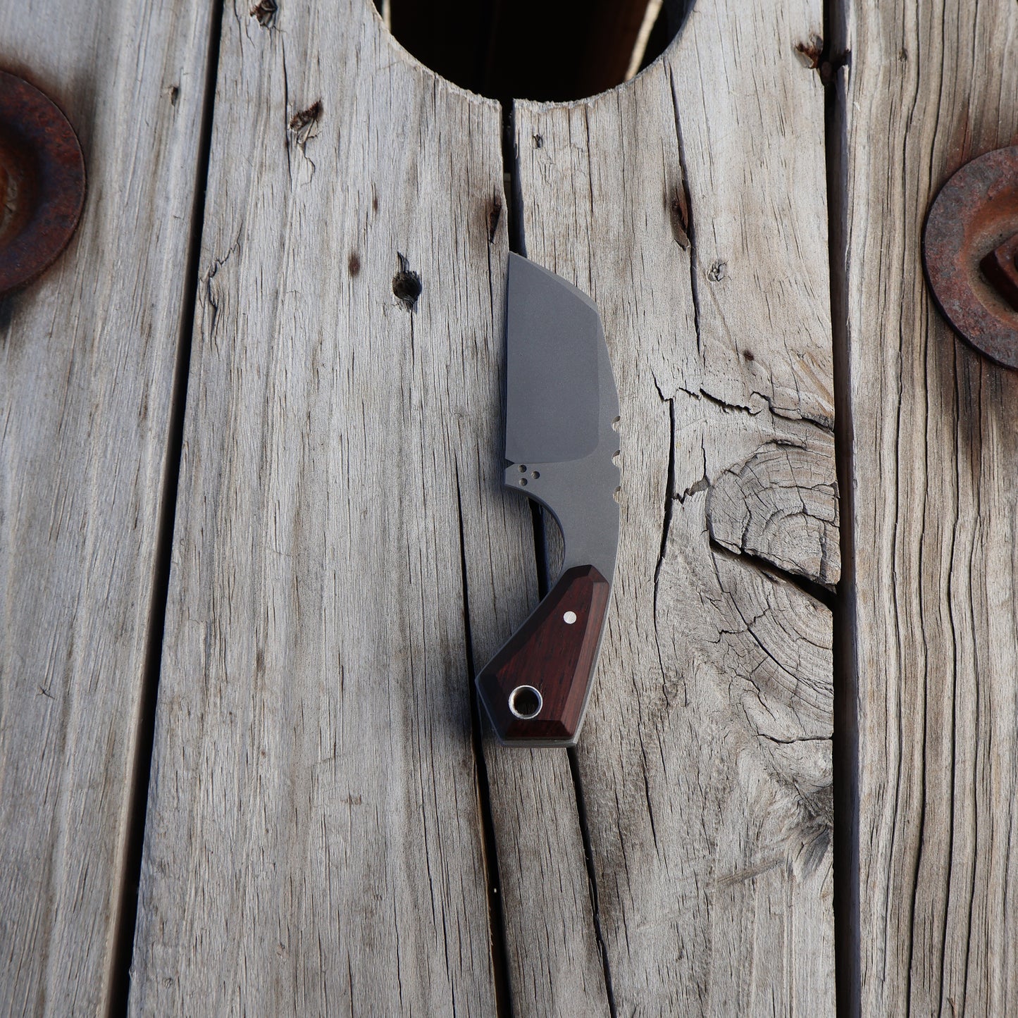knife with wooden handle sitting on wooden surface 