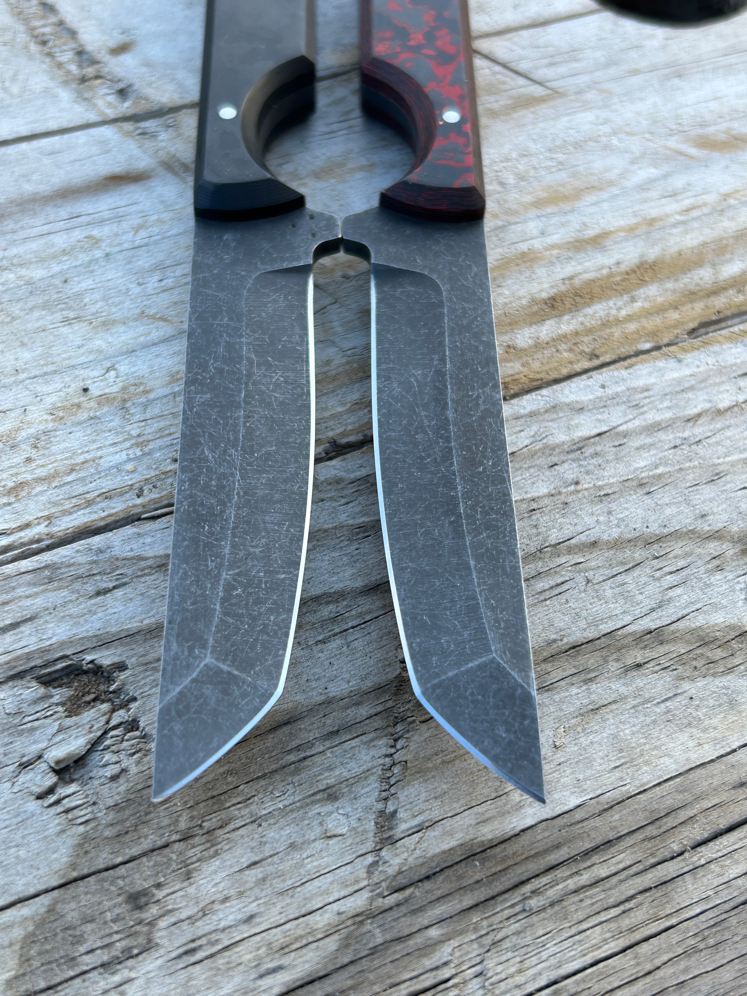 two tanto knives laying edge to edge on wooden surface 