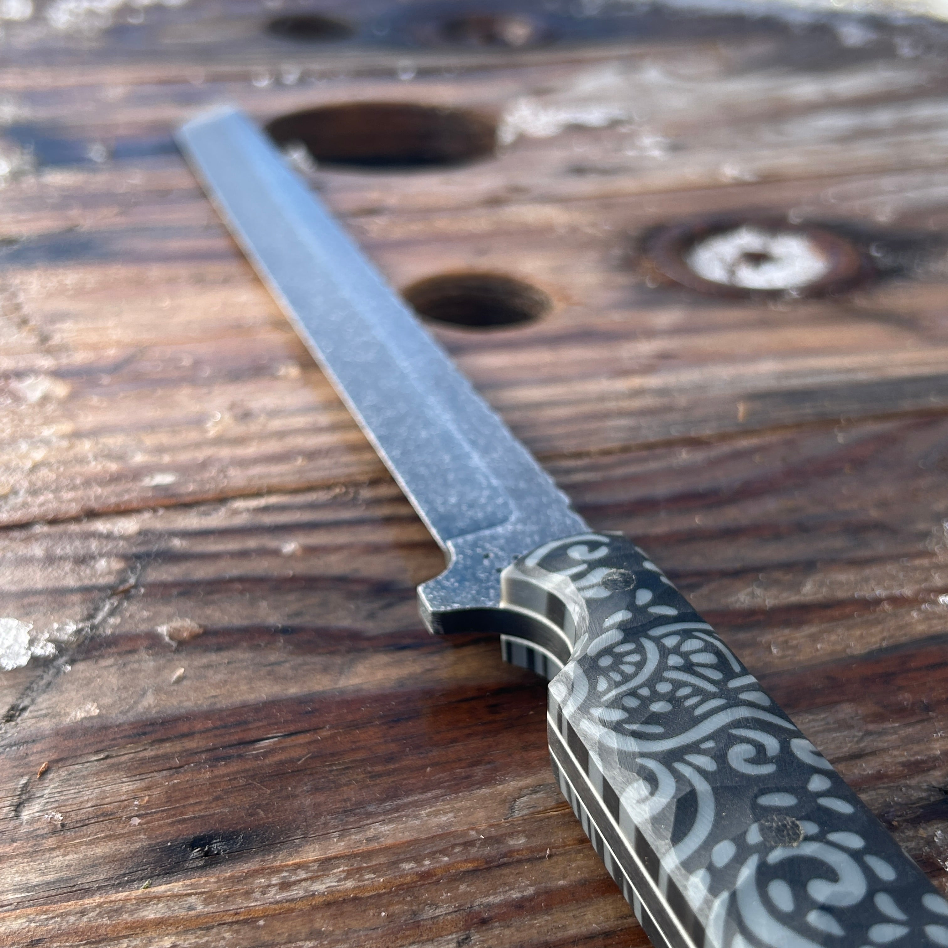 patterned sword handled sword sitting on wood surface 