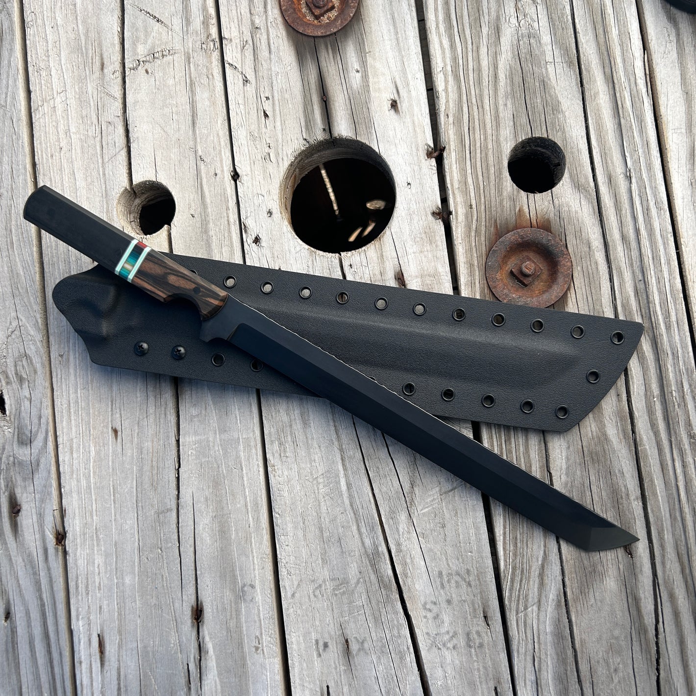 Black sword with sheath on a wooden surface