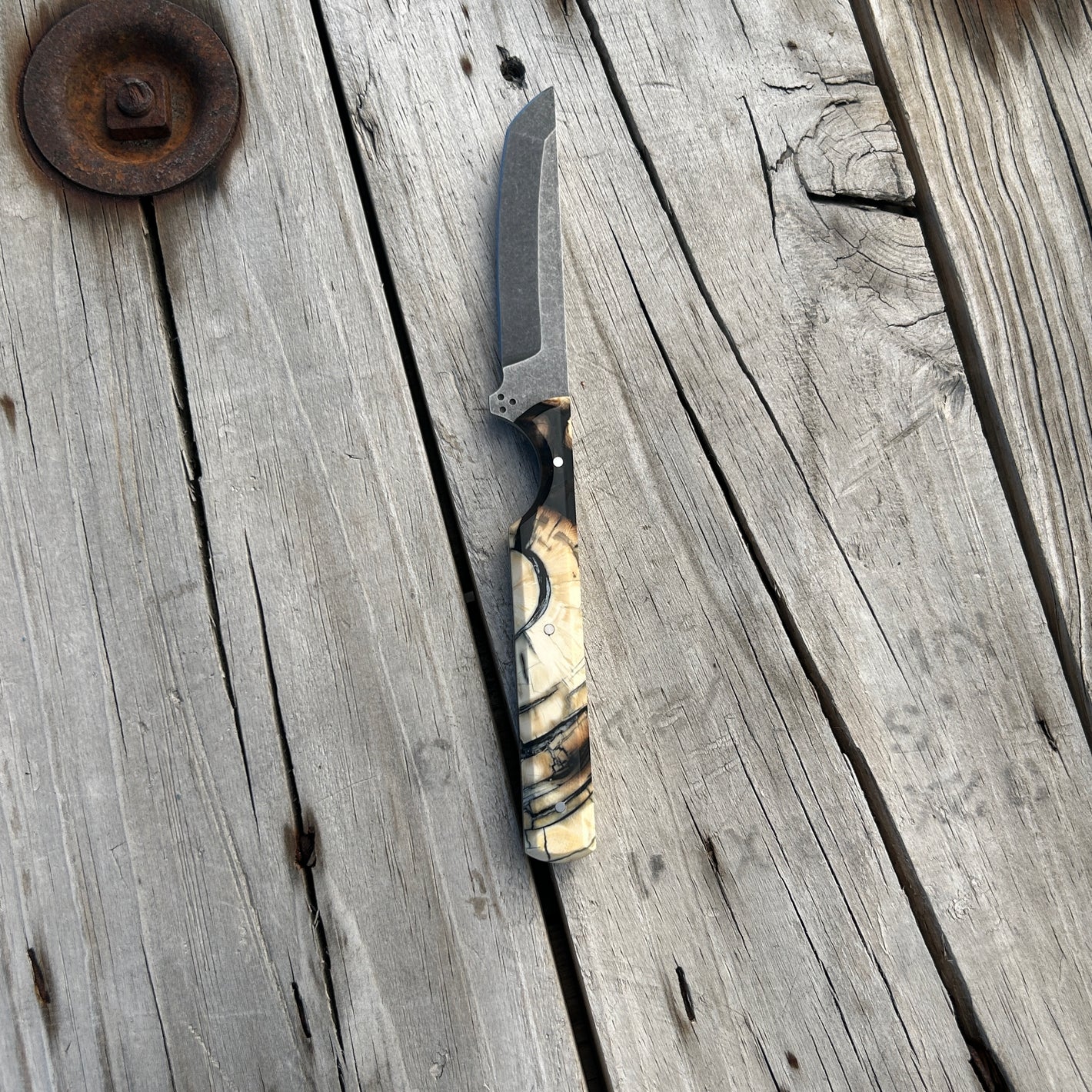 Knife with bone handle sitting on wooden surface 