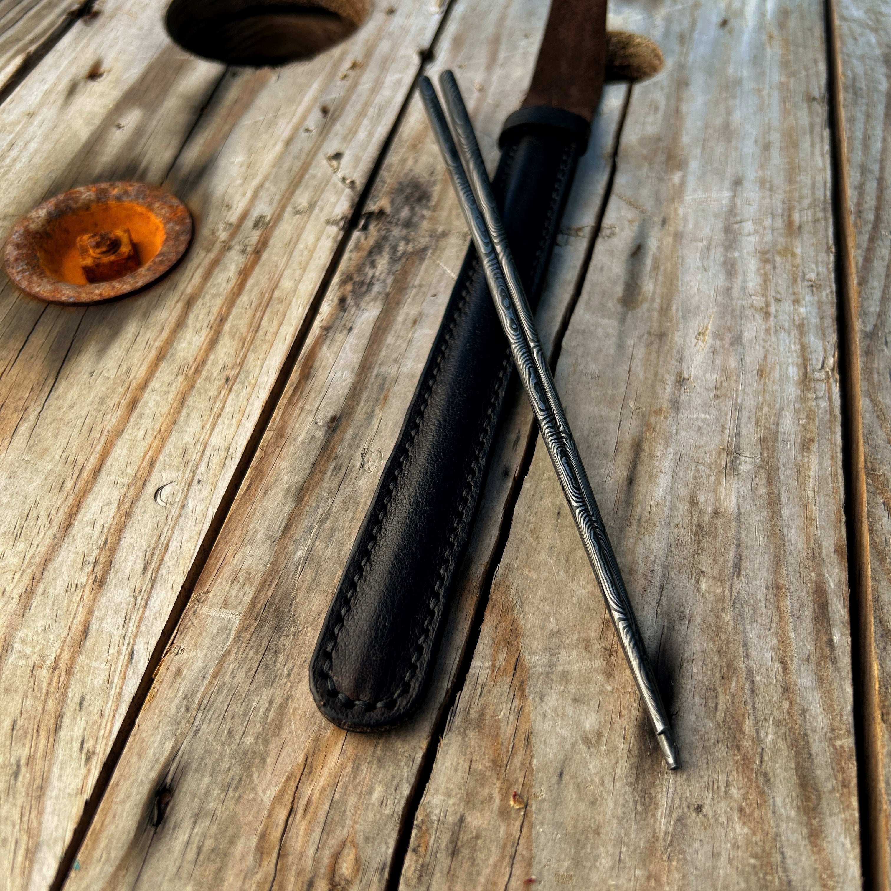 Damascus chopsticks propped up on leather case