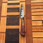 Beautiful Japanese styled paring knife with a black and silver blade and red and tan wood handle