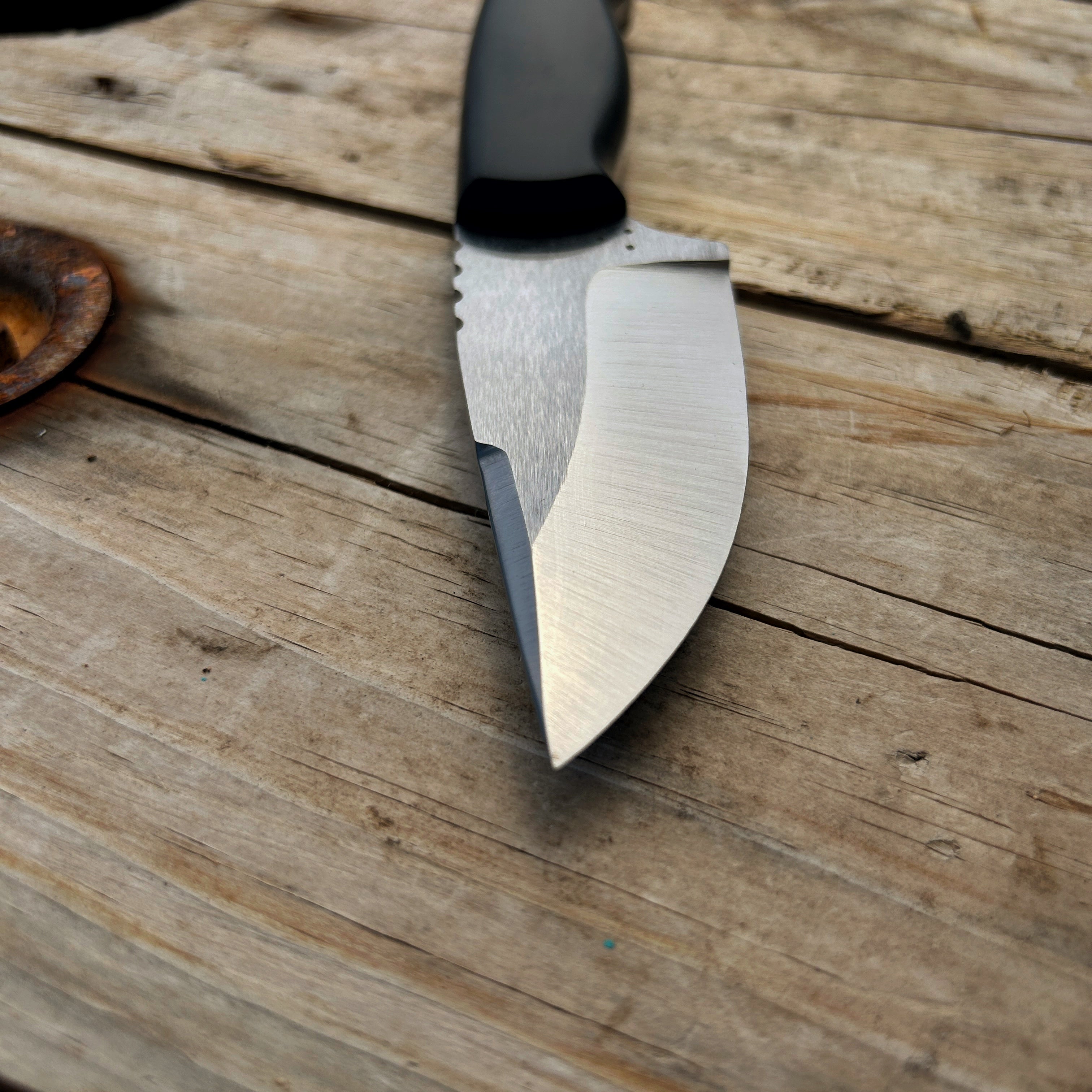 fixed blade with black handle laying on wooden surface 